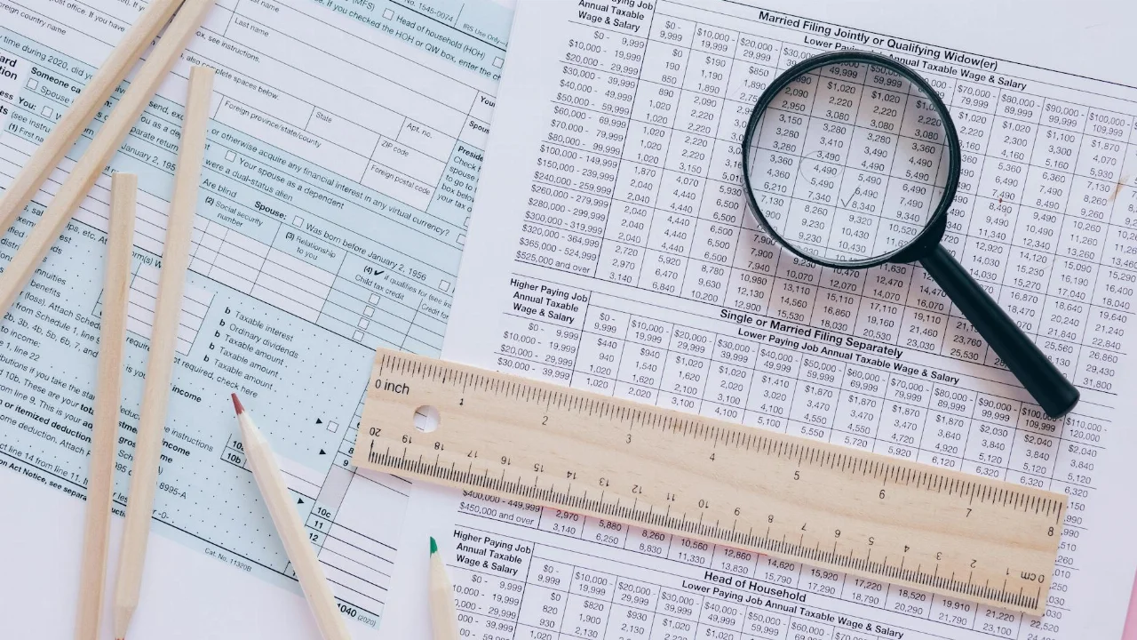 A high angle view showing IRS tax forms with pencils, ruler, and magnifying glass for financial planning.