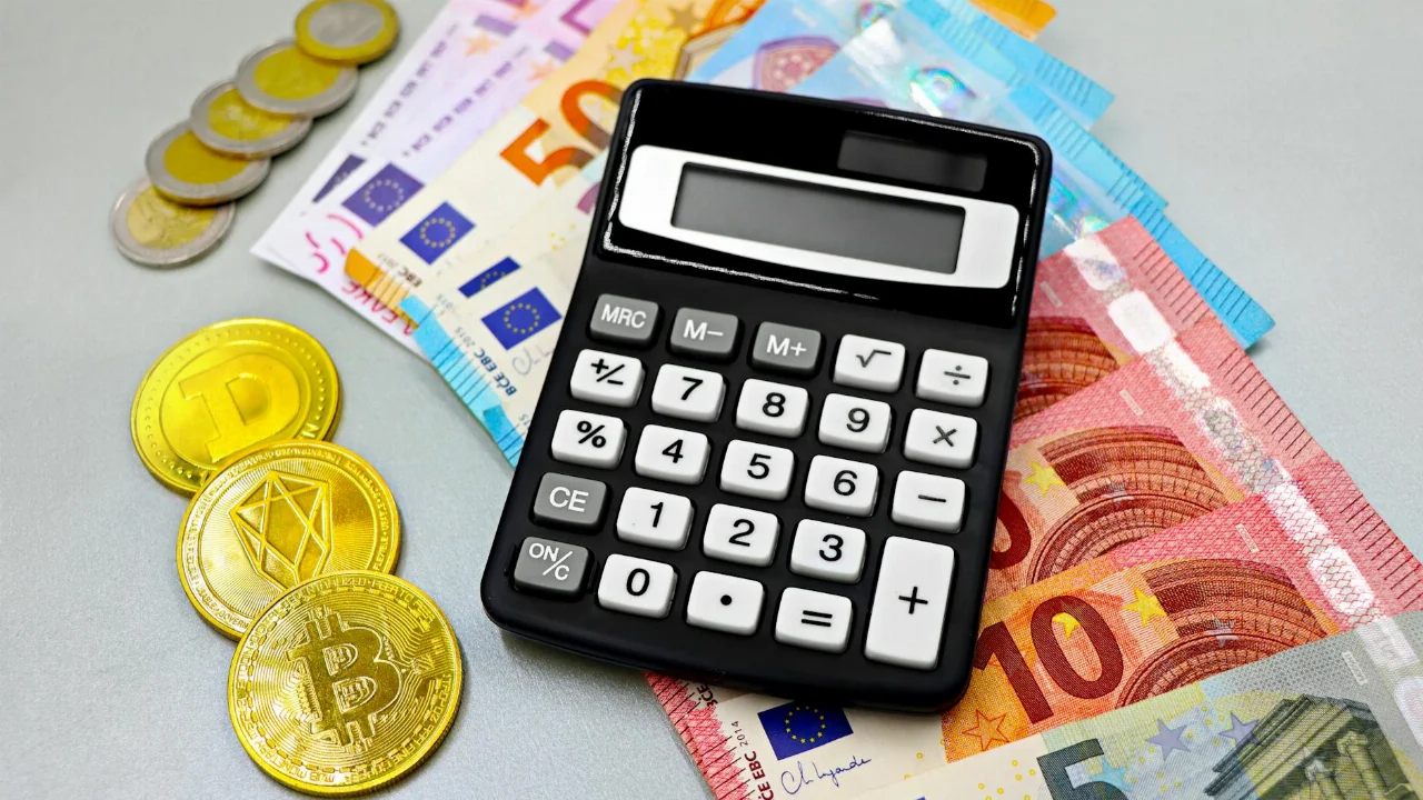 Calculator with euro banknotes and cryptocurrency coins like Bitcoin on a table.