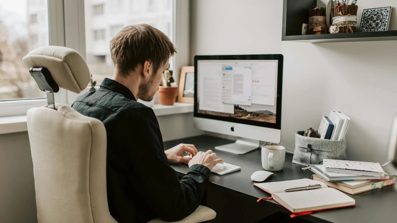 A man in a home office setting working on a computer with a relaxed and focused atmosphere.