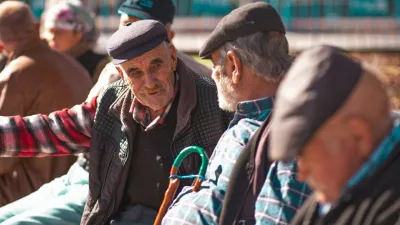 A group of senior men with hats talk and relax on a sunny day, showcasing warmth and friendship.